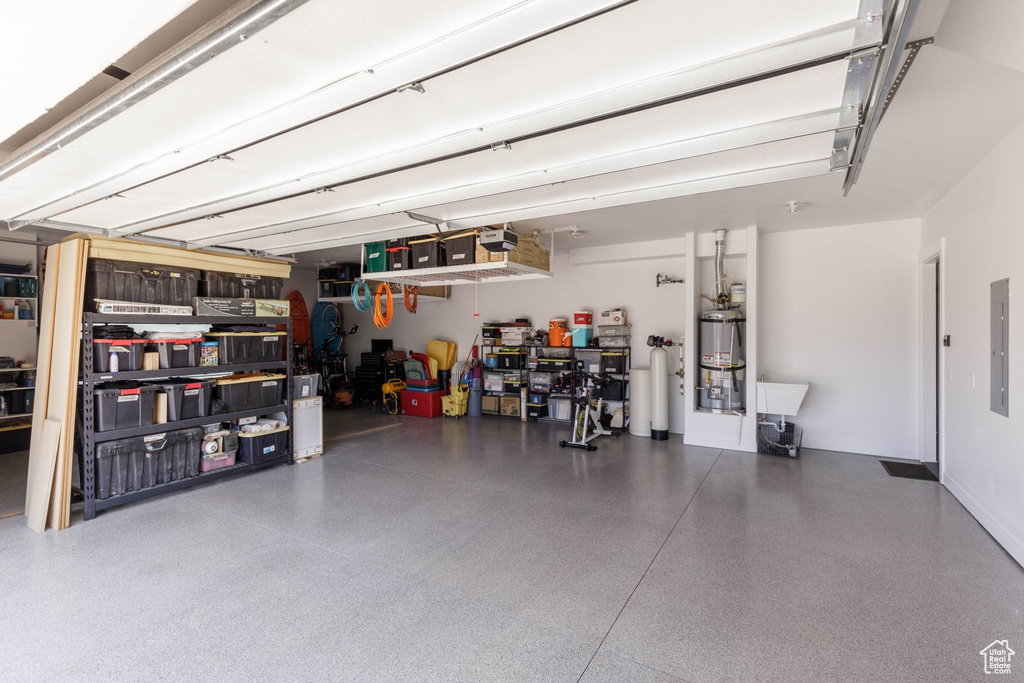 Garage featuring a garage door opener, secured water heater, and electric panel