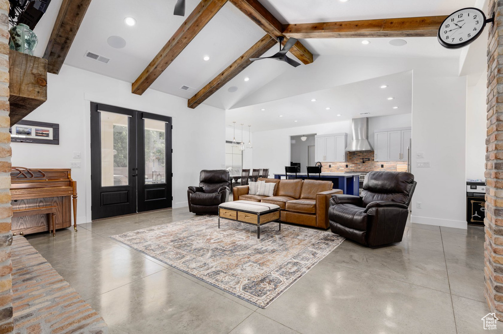 Living room featuring french doors, beam ceiling, high vaulted ceiling, brick wall, and concrete floors