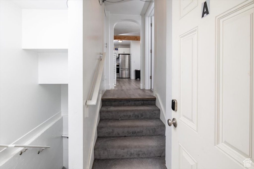 Stairs featuring beamed ceiling and wood-type flooring