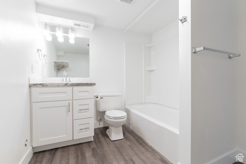 Full bathroom with toilet, bathtub / shower combination, hardwood / wood-style floors, and vanity