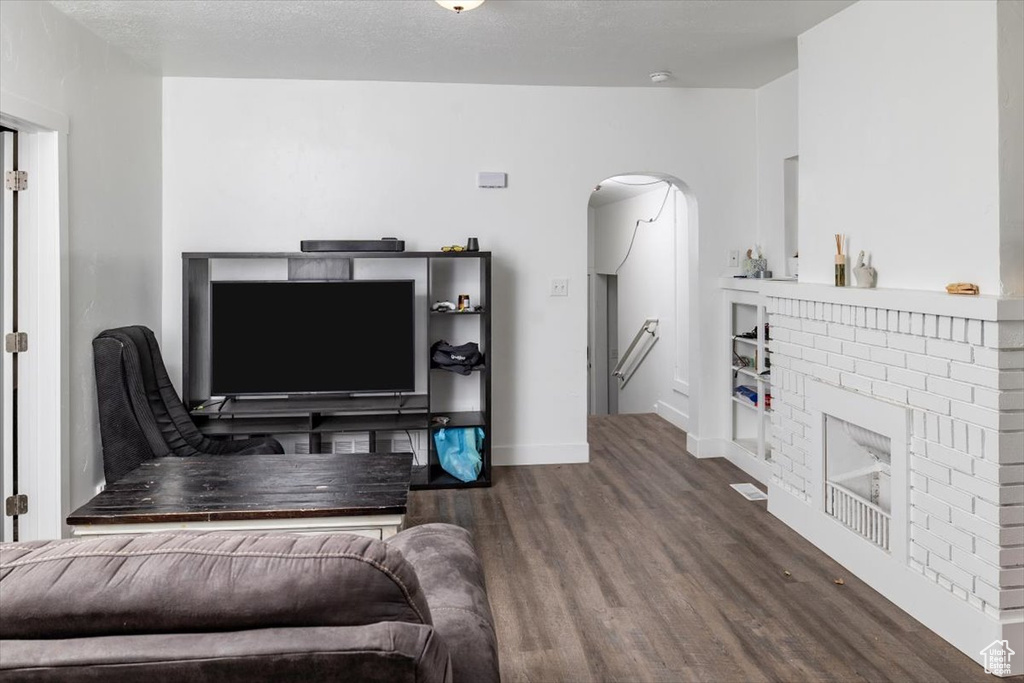 Living room with dark hardwood / wood-style flooring and a fireplace