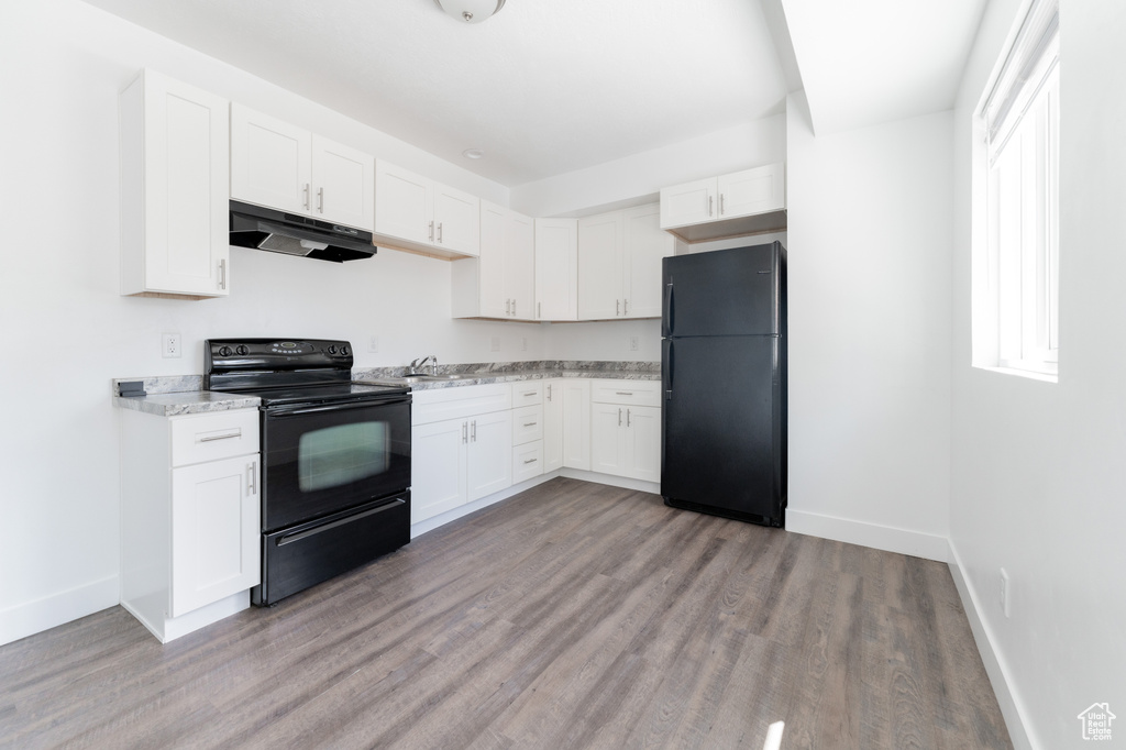 Kitchen featuring sink, hardwood / wood-style flooring, black appliances, and white cabinets