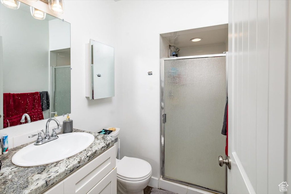 Bathroom with vanity, an enclosed shower, and toilet