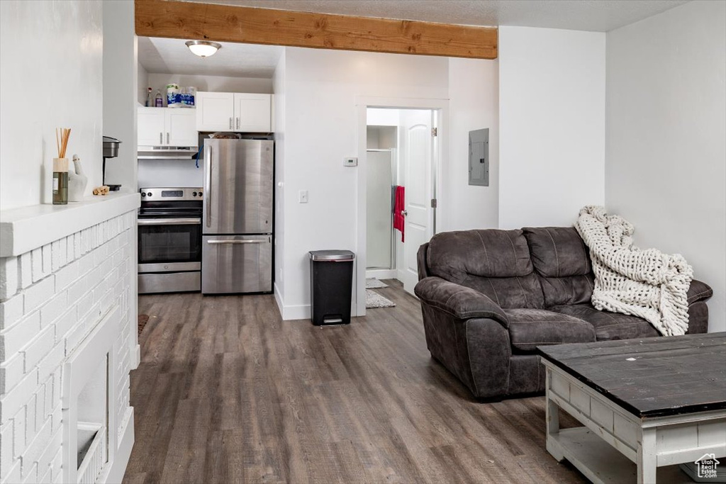 Living room featuring dark wood-type flooring, electric panel, and beam ceiling