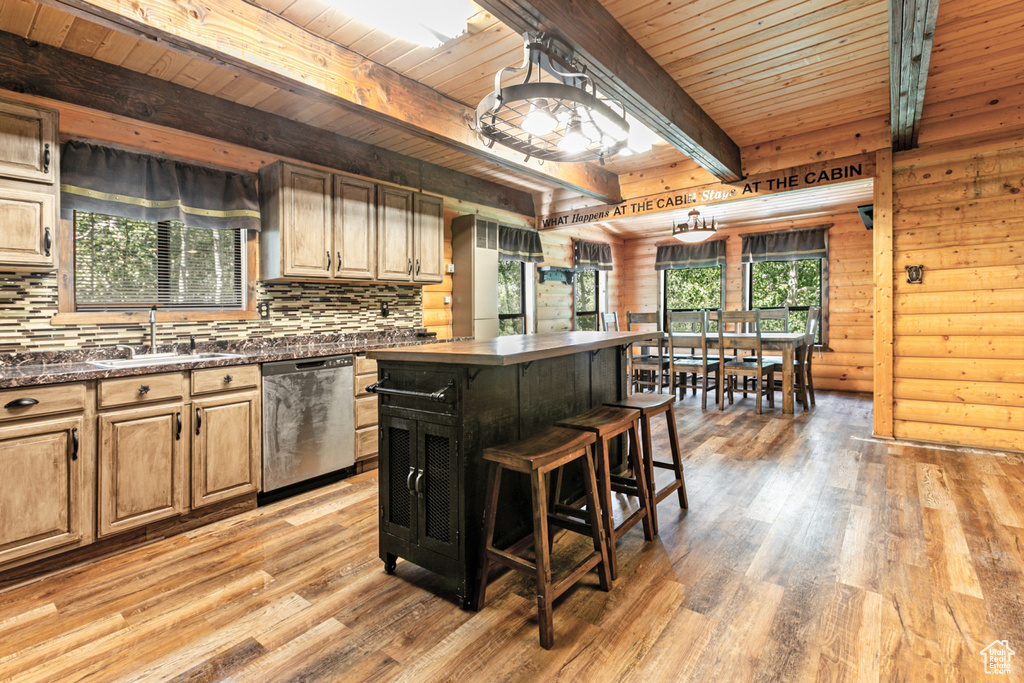 Kitchen featuring beam ceiling, light hardwood / wood-style flooring, log walls, and stainless steel dishwasher