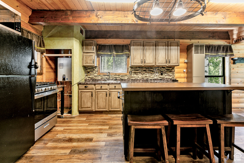 Kitchen with stainless steel range with gas cooktop, a wealth of natural light, light wood-type flooring, and wood ceiling