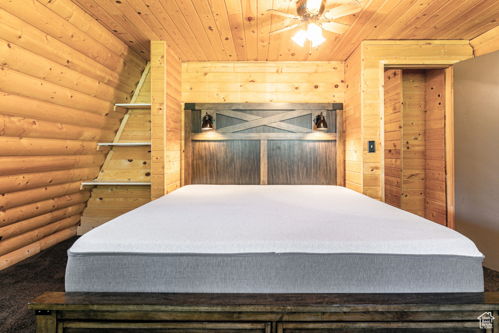 Bedroom with wooden ceiling, ceiling fan, and rustic walls