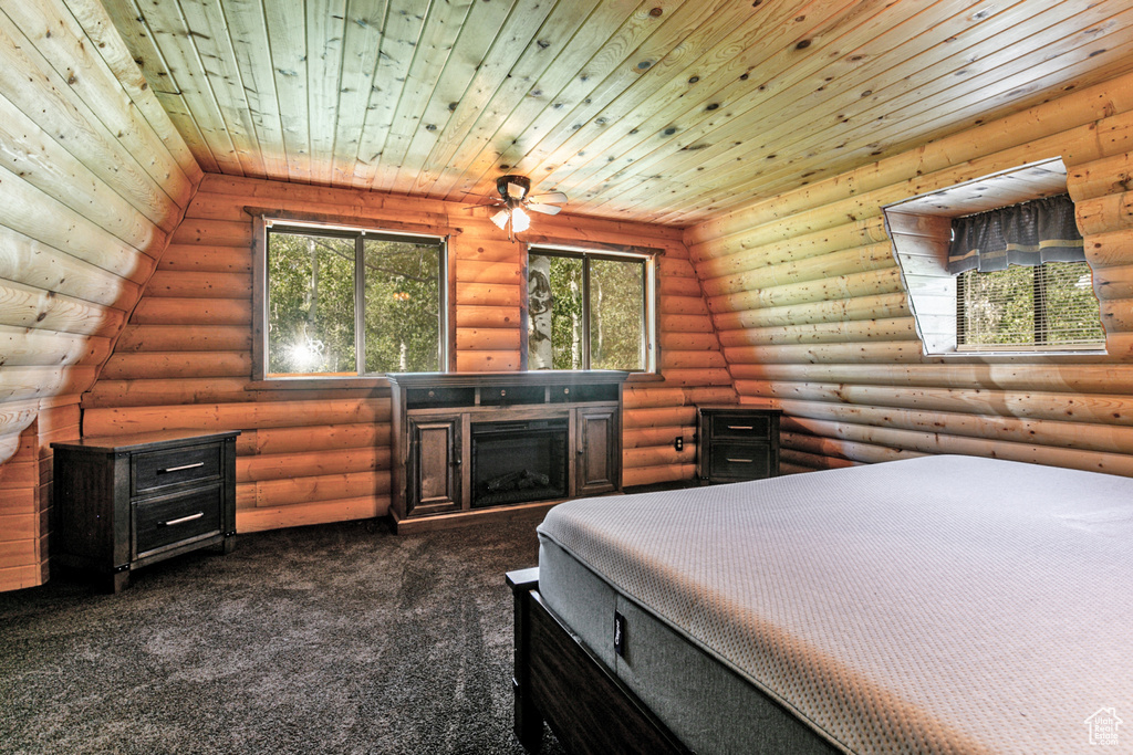 Carpeted bedroom featuring wood ceiling, a fireplace, and rustic walls