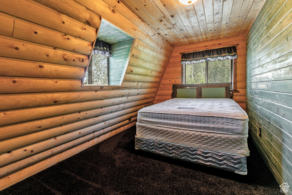 Unfurnished bedroom featuring lofted ceiling, rustic walls, carpet floors, and wooden ceiling