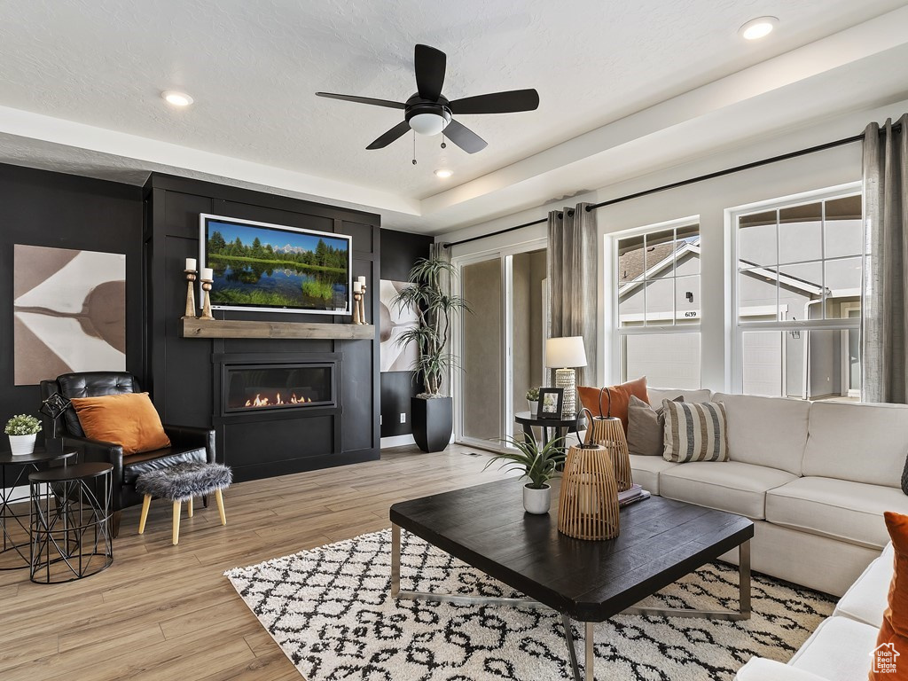 Living room featuring ceiling fan, light hardwood / wood-style flooring, and a raised ceiling