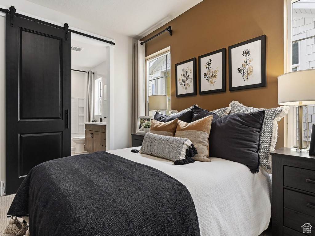 Bedroom featuring a barn door and ensuite bathroom