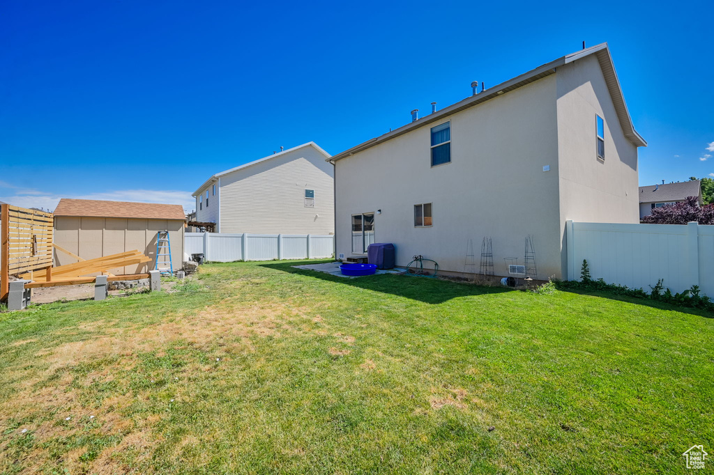 Back of property featuring a storage shed and a yard