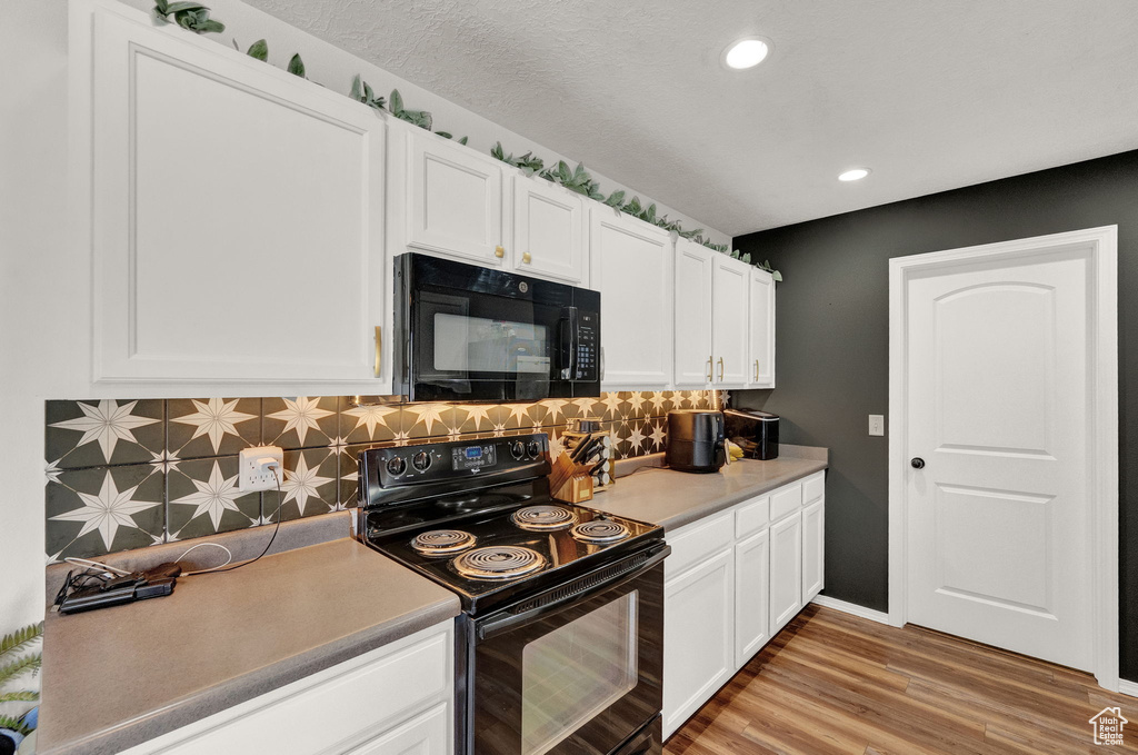 Kitchen with white cabinetry, black appliances, and decorative backsplash