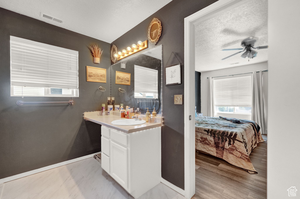 Bathroom featuring a textured ceiling, hardwood / wood-style floors, vanity, and ceiling fan