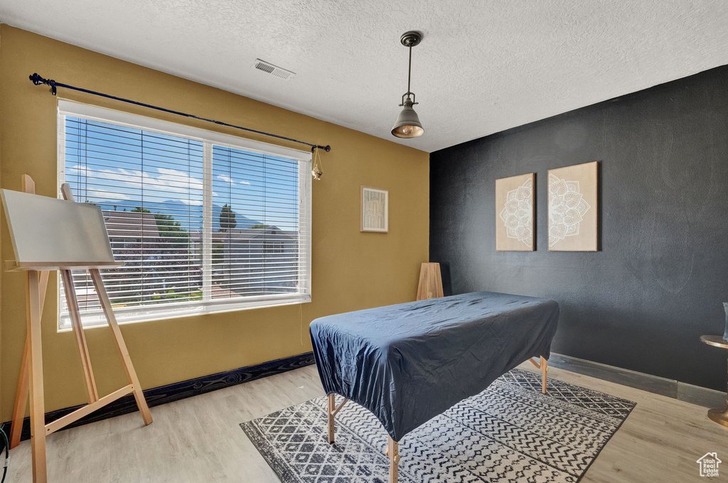 Bedroom with a textured ceiling and light wood-type flooring