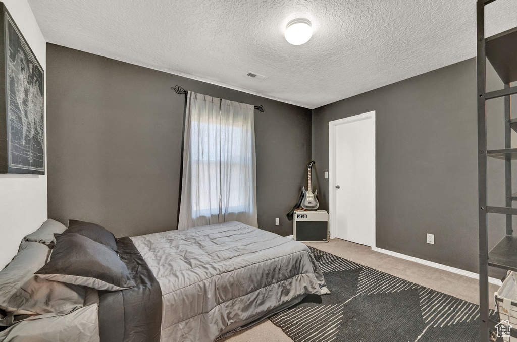 Bedroom with a textured ceiling and carpet flooring