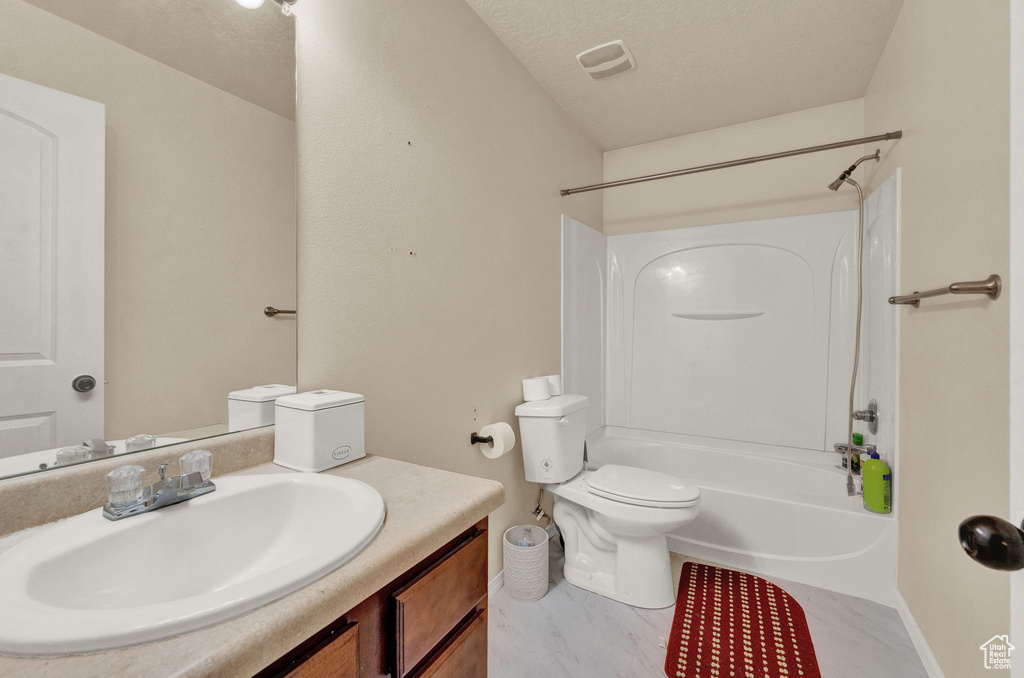 Full bathroom with vanity, tile patterned floors, washtub / shower combination, toilet, and a textured ceiling