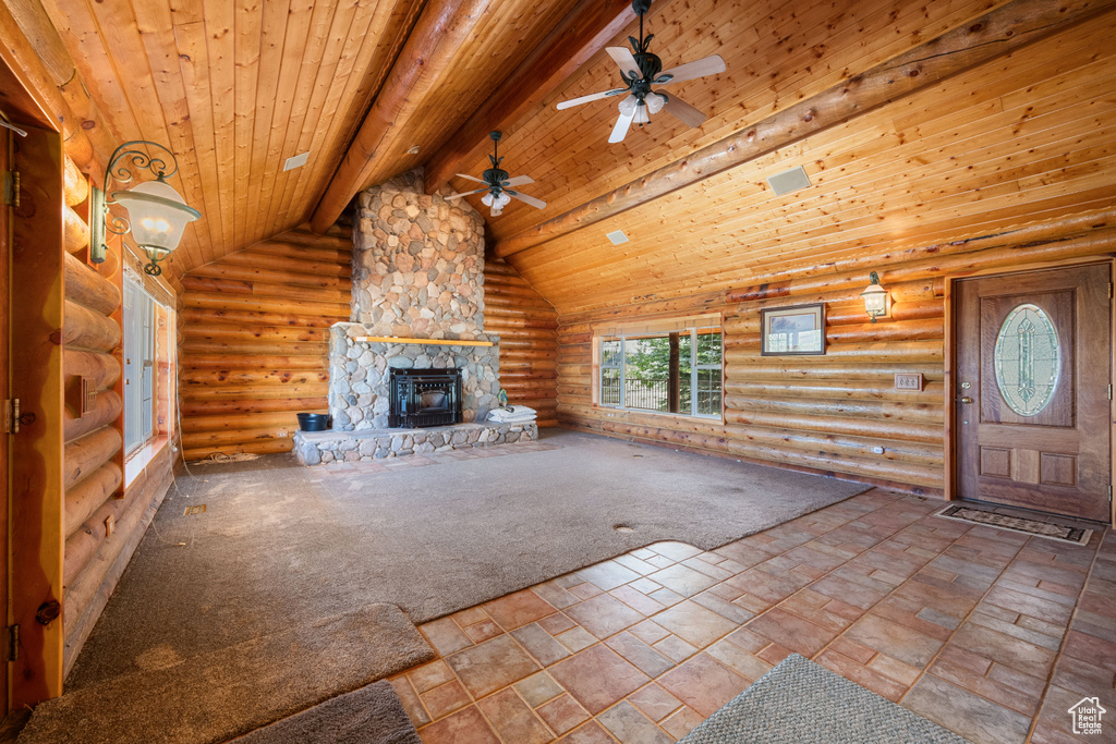 Unfurnished living room featuring wood ceiling, tile patterned flooring, rustic walls, beam ceiling, and ceiling fan