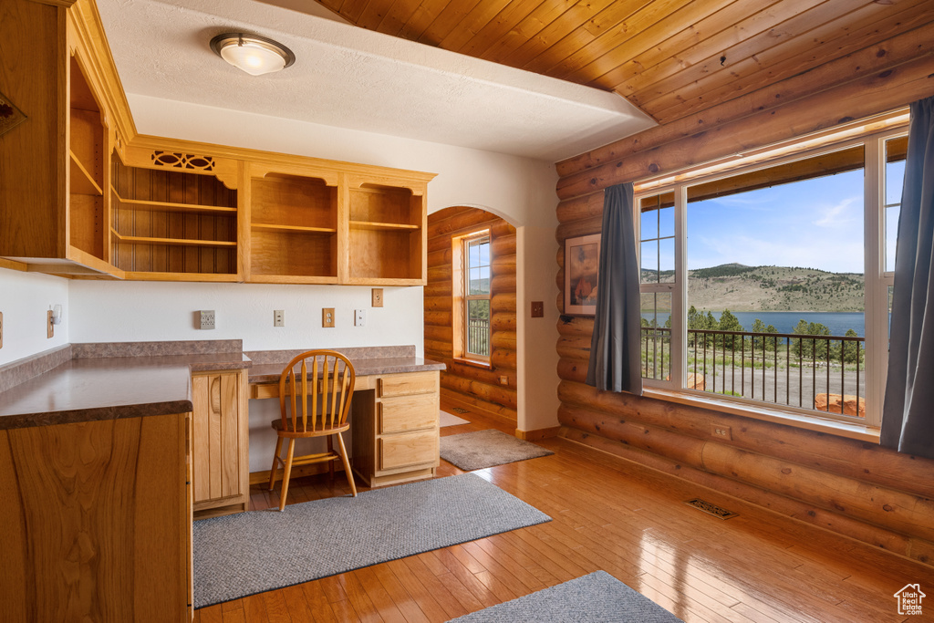 Unfurnished office with a healthy amount of sunlight, wood-type flooring, and log walls