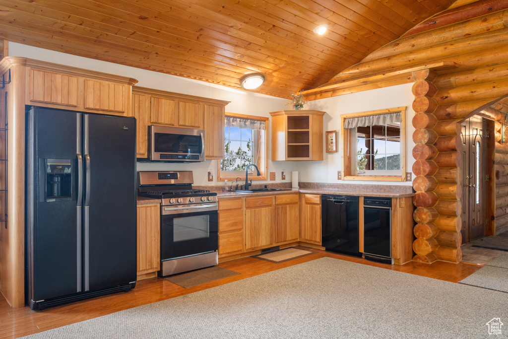 Kitchen featuring black appliances, a wealth of natural light, and rustic walls