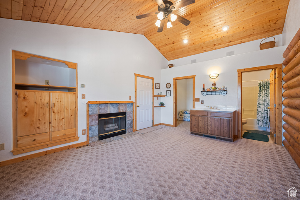 Carpeted living room with a tile fireplace, wooden ceiling, and ceiling fan