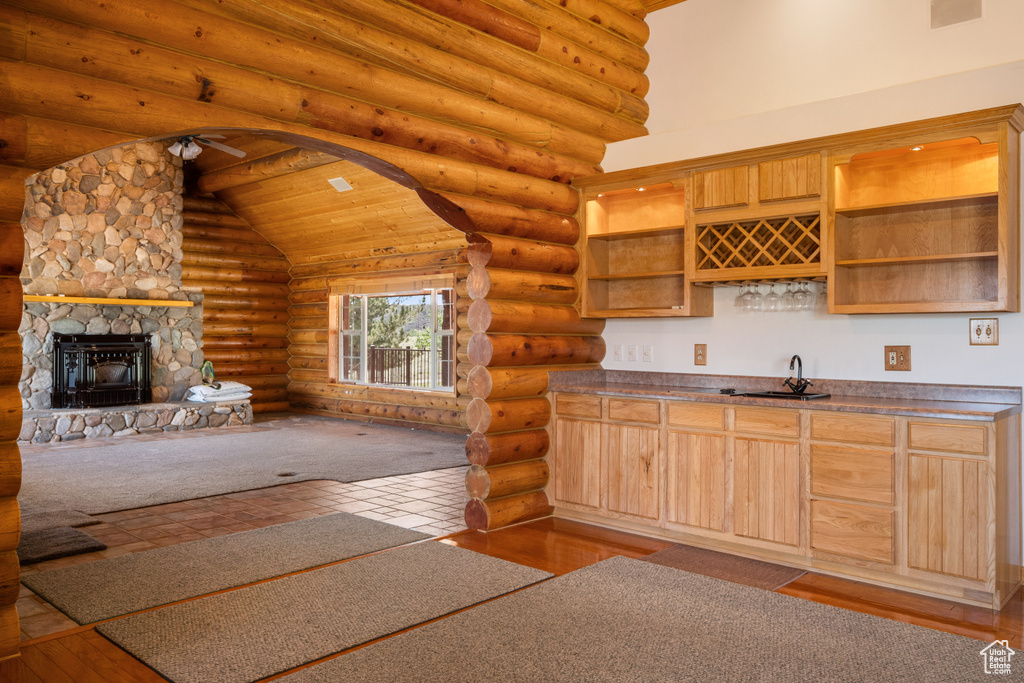 Kitchen featuring log walls, wood ceiling, a fireplace, light hardwood / wood-style floors, and high vaulted ceiling