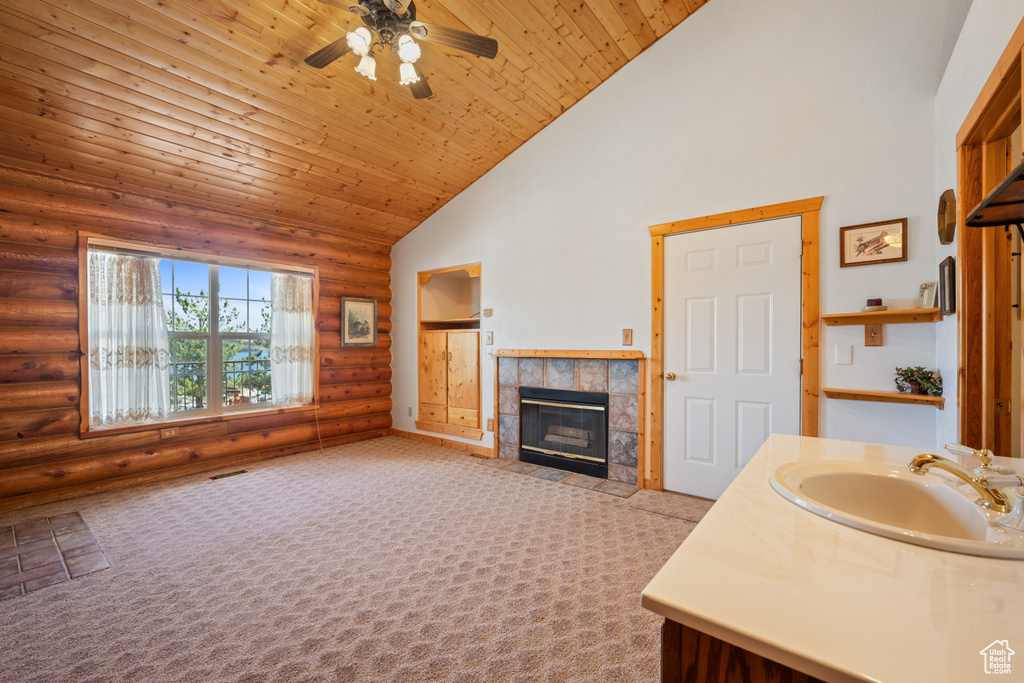 Interior space with sink, light carpet, a tiled fireplace, and rustic walls