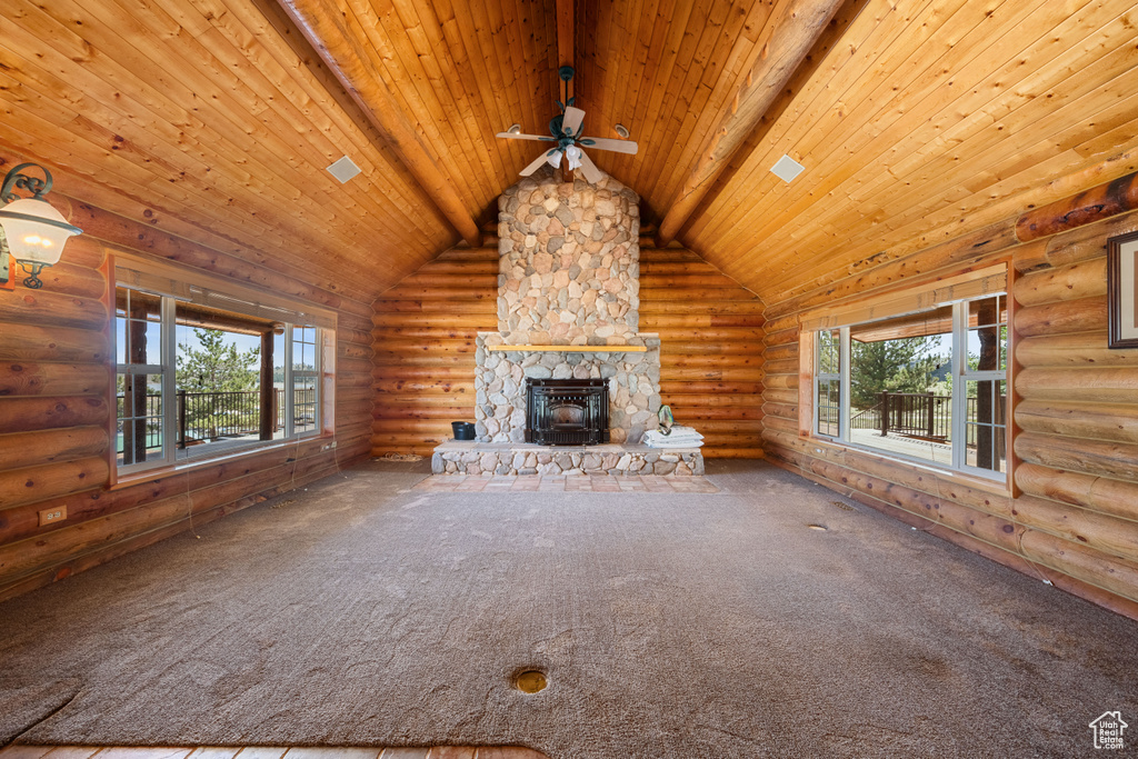 Unfurnished living room featuring rustic walls, ceiling fan, wooden ceiling, a fireplace, and carpet