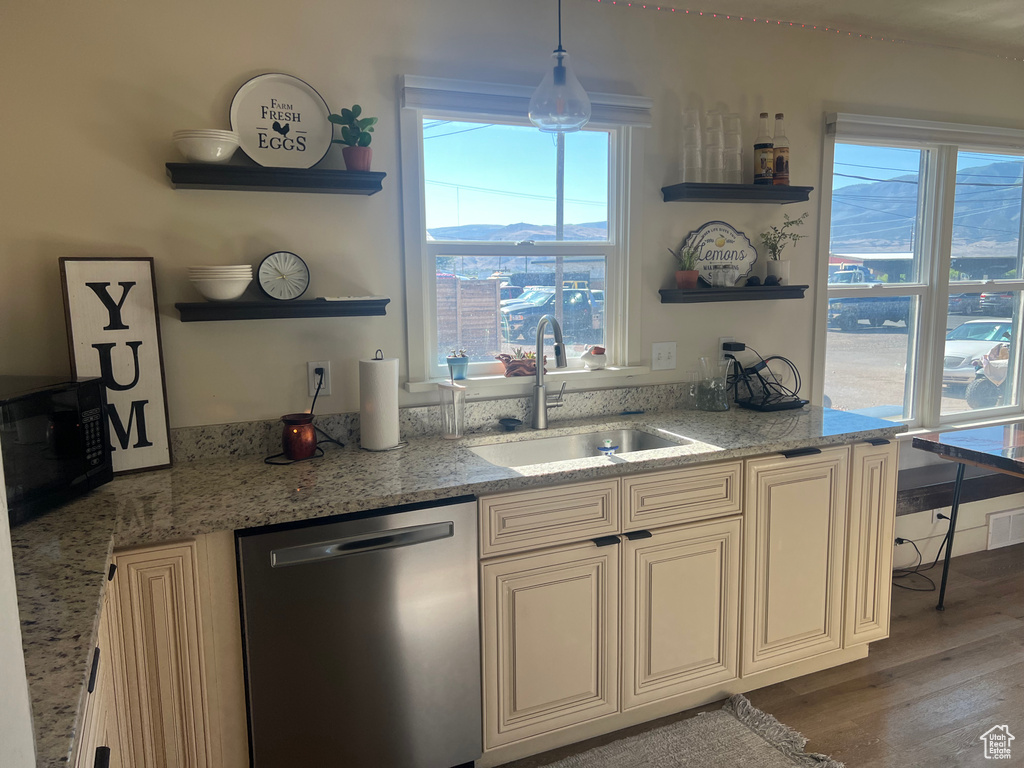 Kitchen featuring decorative light fixtures, cream cabinets, hardwood / wood-style floors, sink, and dishwasher