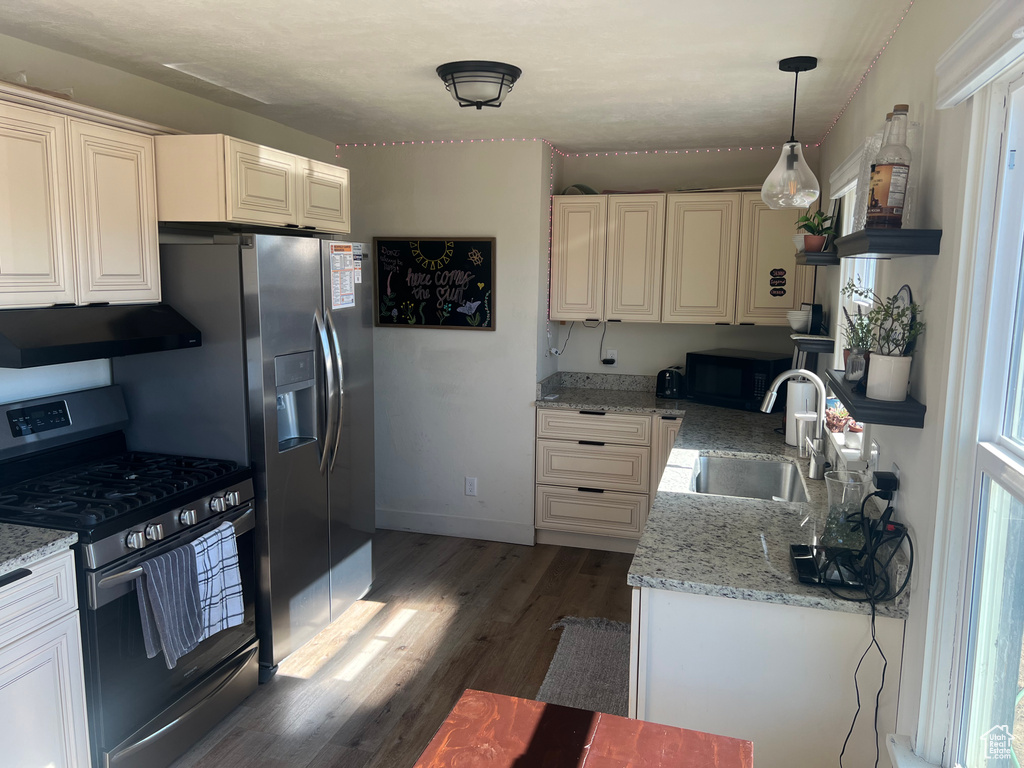 Kitchen featuring appliances with stainless steel finishes, sink, decorative light fixtures, dark hardwood / wood-style floors, and light stone countertops