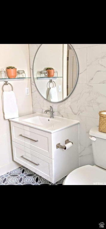 Bathroom featuring vanity, tile walls, toilet, and tile patterned flooring