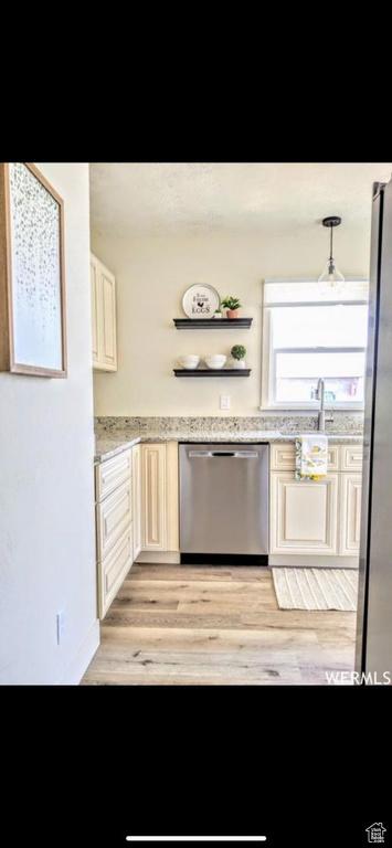 Kitchen with stainless steel appliances, hanging light fixtures, sink, light hardwood / wood-style flooring, and light stone counters