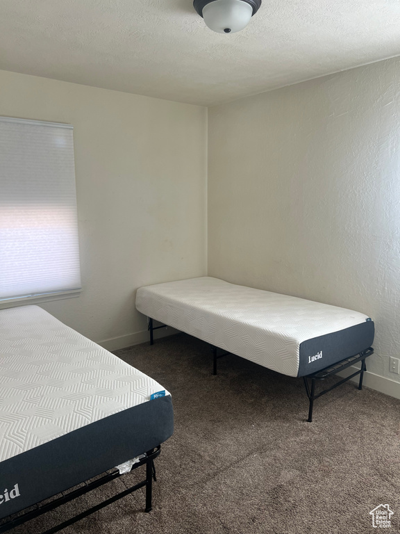 Bedroom featuring a textured ceiling and dark carpet