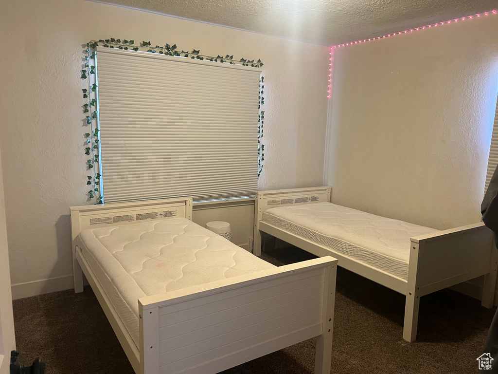 Unfurnished bedroom featuring a textured ceiling and dark carpet