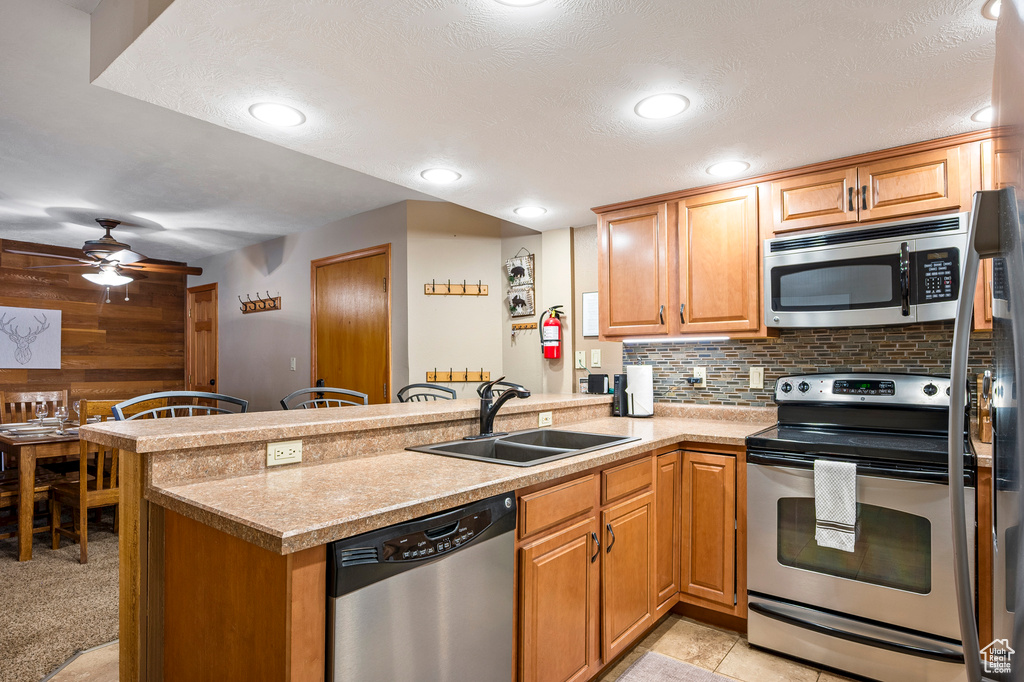 Kitchen featuring sink, appliances with stainless steel finishes, kitchen peninsula, and a textured ceiling