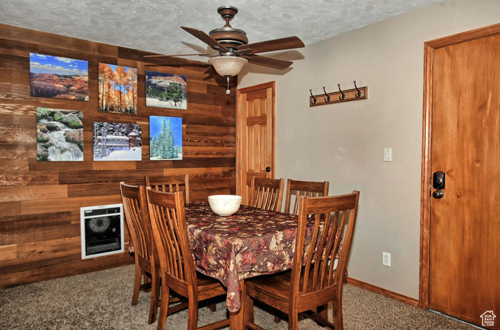 Dining room with a textured ceiling, carpet floors, and ceiling fan