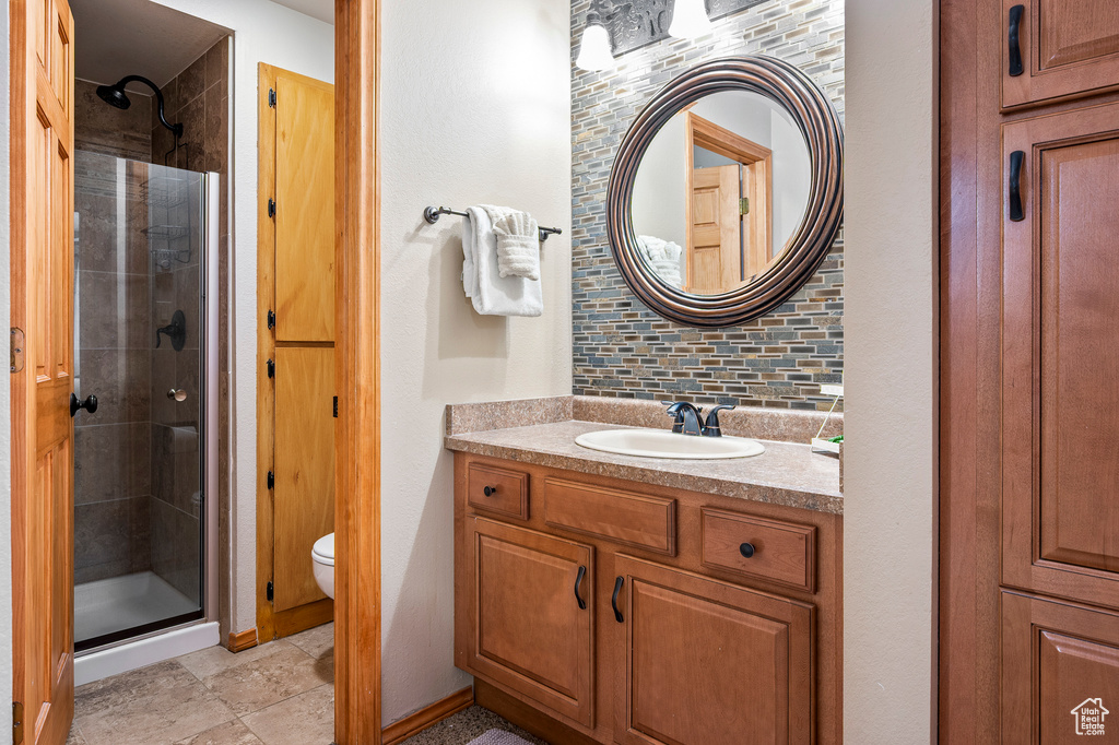 Bathroom with walk in shower, vanity, toilet, and tasteful backsplash