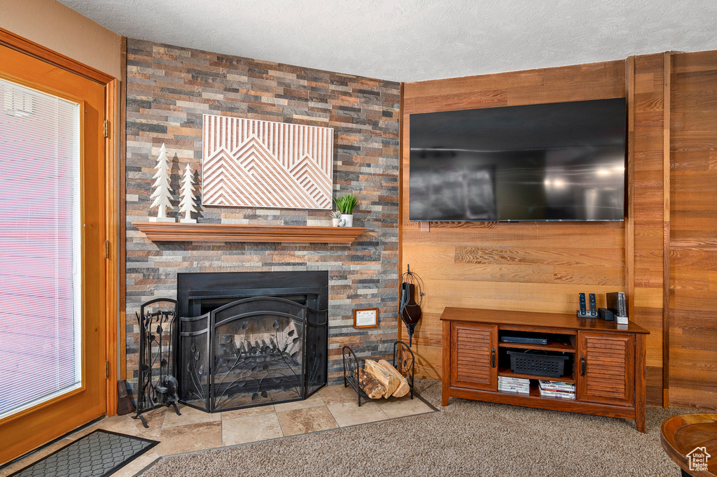 Carpeted living room with a large fireplace, wood walls, and a textured ceiling