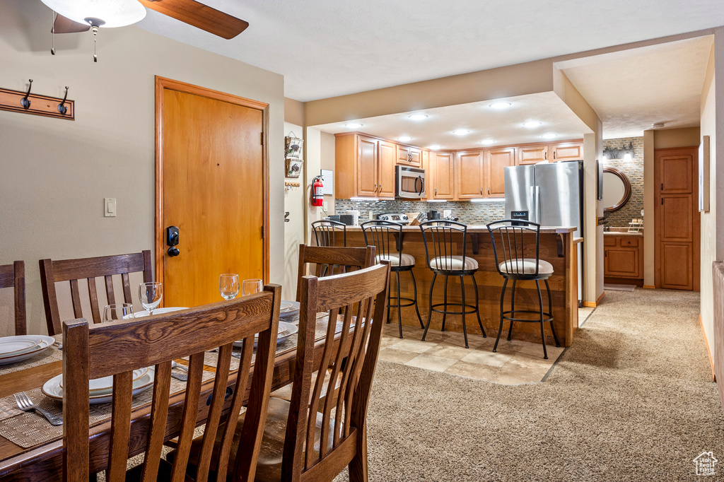 Dining area featuring ceiling fan and light colored carpet