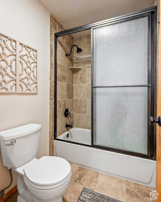 Bathroom featuring bath / shower combo with glass door and toilet