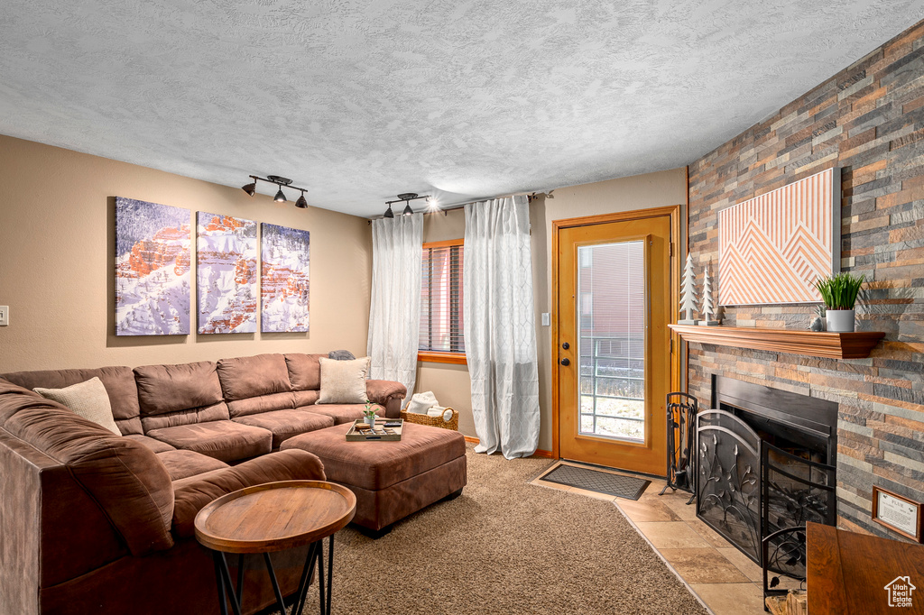 Carpeted living room with a textured ceiling, a large fireplace, and track lighting