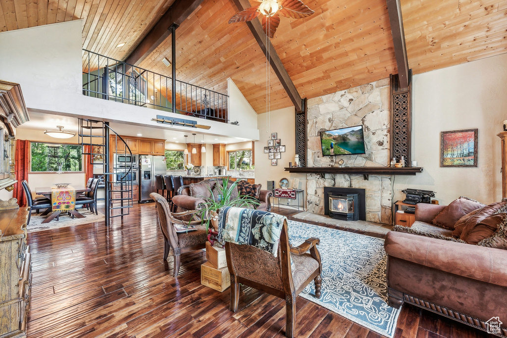 Living room featuring high vaulted ceiling, wooden ceiling, ceiling fan, and a fireplace