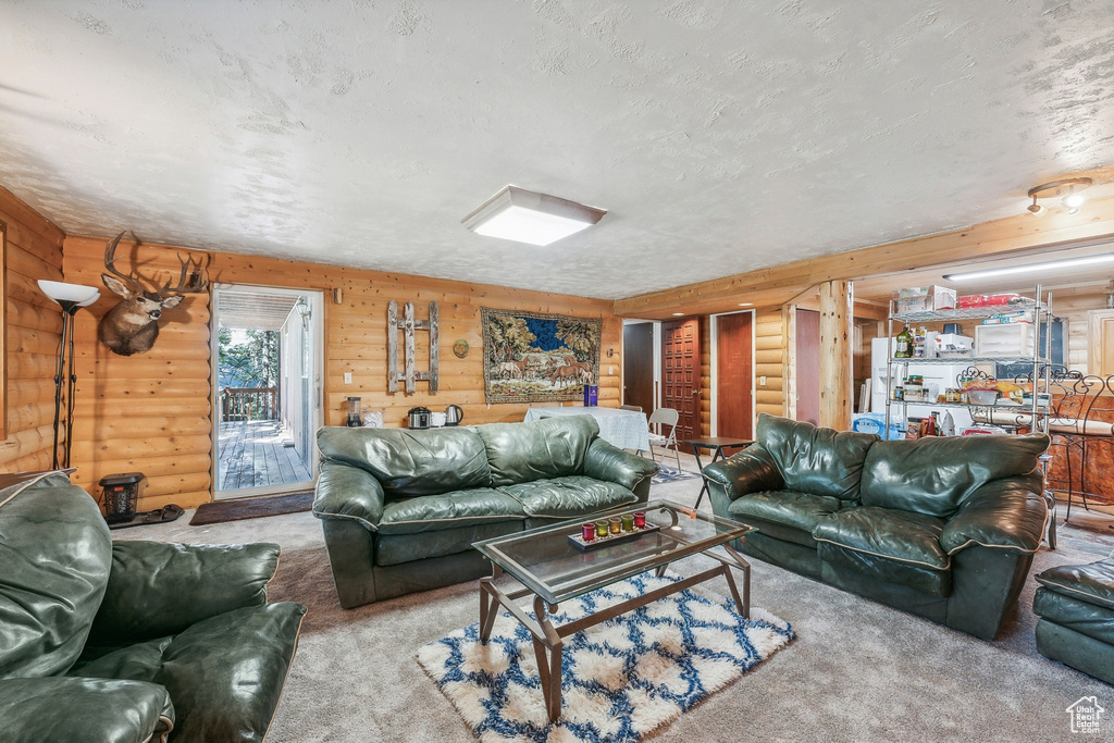 Carpeted living room with a textured ceiling, wood walls, and rustic walls