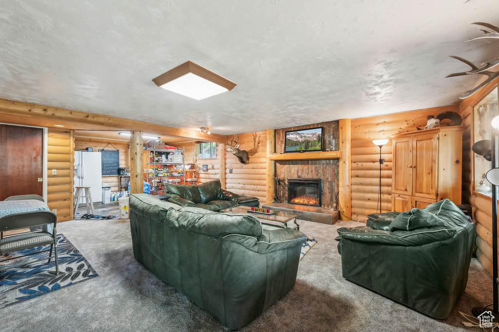 Carpeted living room with log walls, a textured ceiling, and a fireplace