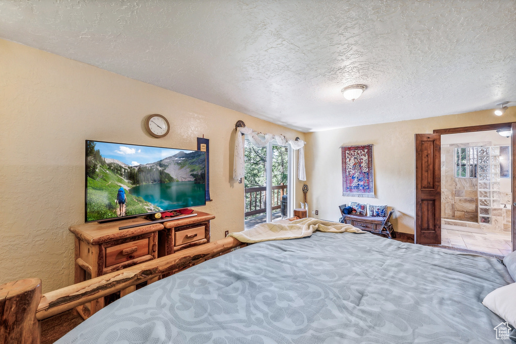 Bedroom with access to outside, a textured ceiling, and ensuite bathroom