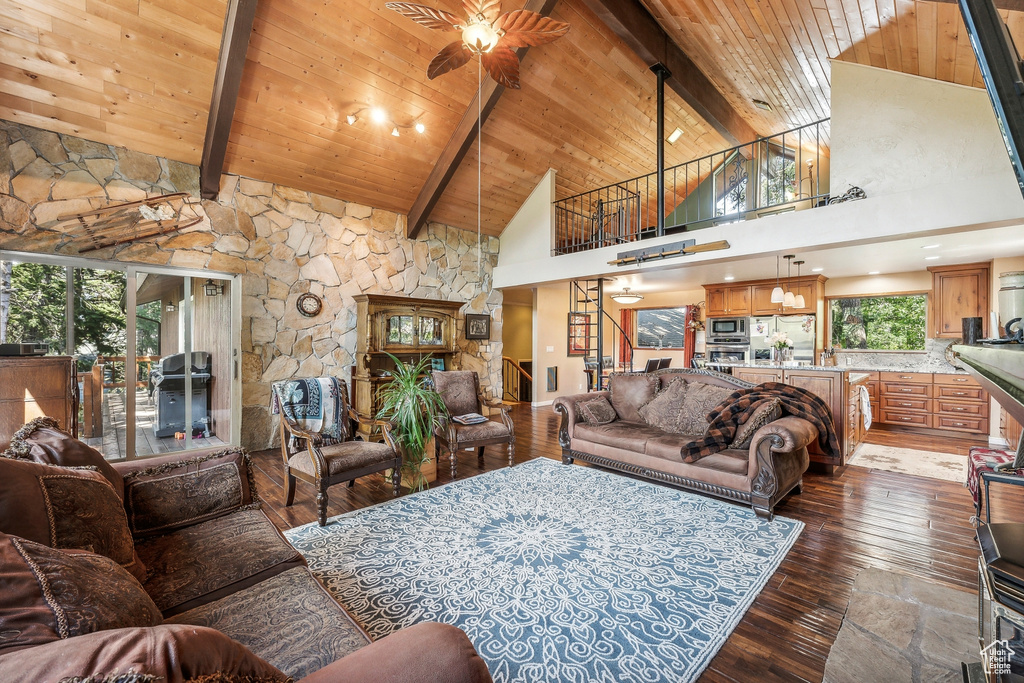 Living room featuring dark hardwood / wood-style floors, beamed ceiling, ceiling fan, and wood ceiling