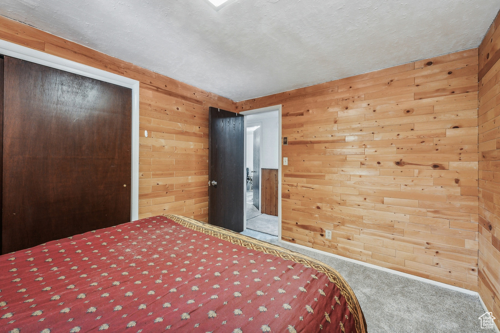 Unfurnished bedroom with a textured ceiling, carpet, and wooden walls