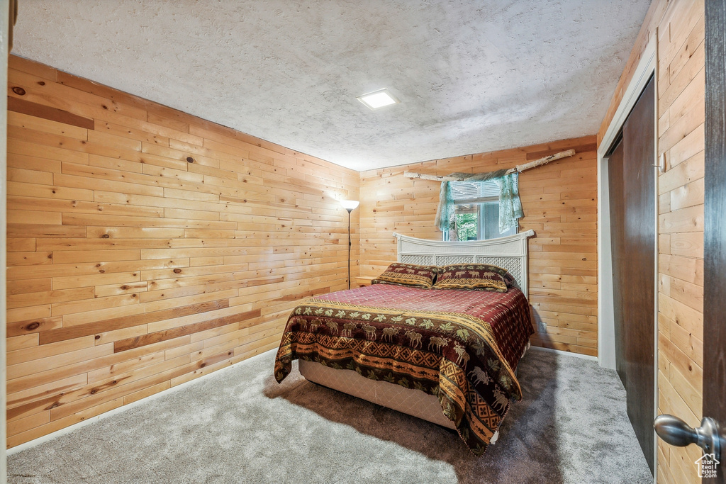 Carpeted bedroom with a textured ceiling and wooden walls