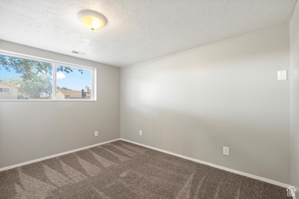 Carpeted empty room featuring a textured ceiling