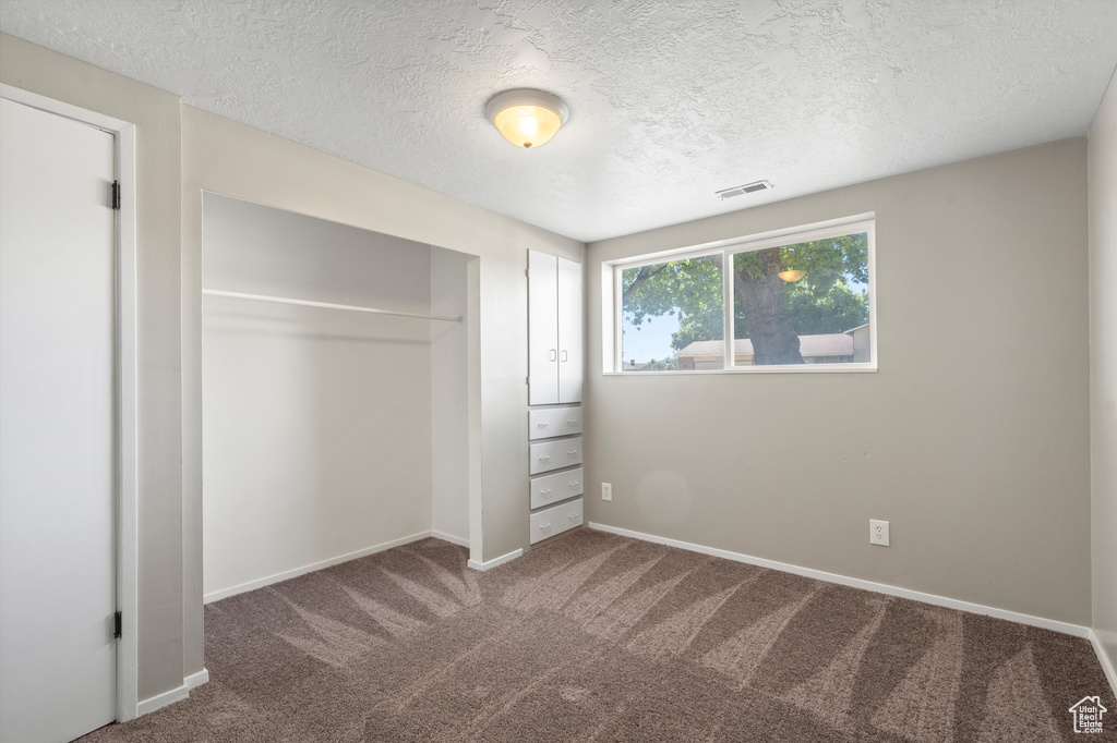 Unfurnished bedroom with a closet, carpet floors, and a textured ceiling